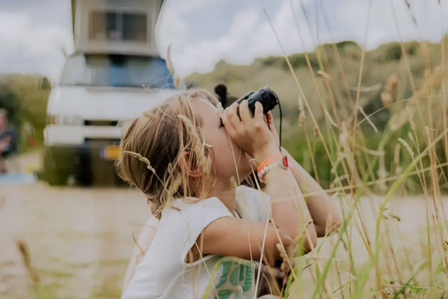 Meisje kijkt doort een verrekijker en kampeeert met haar ouders